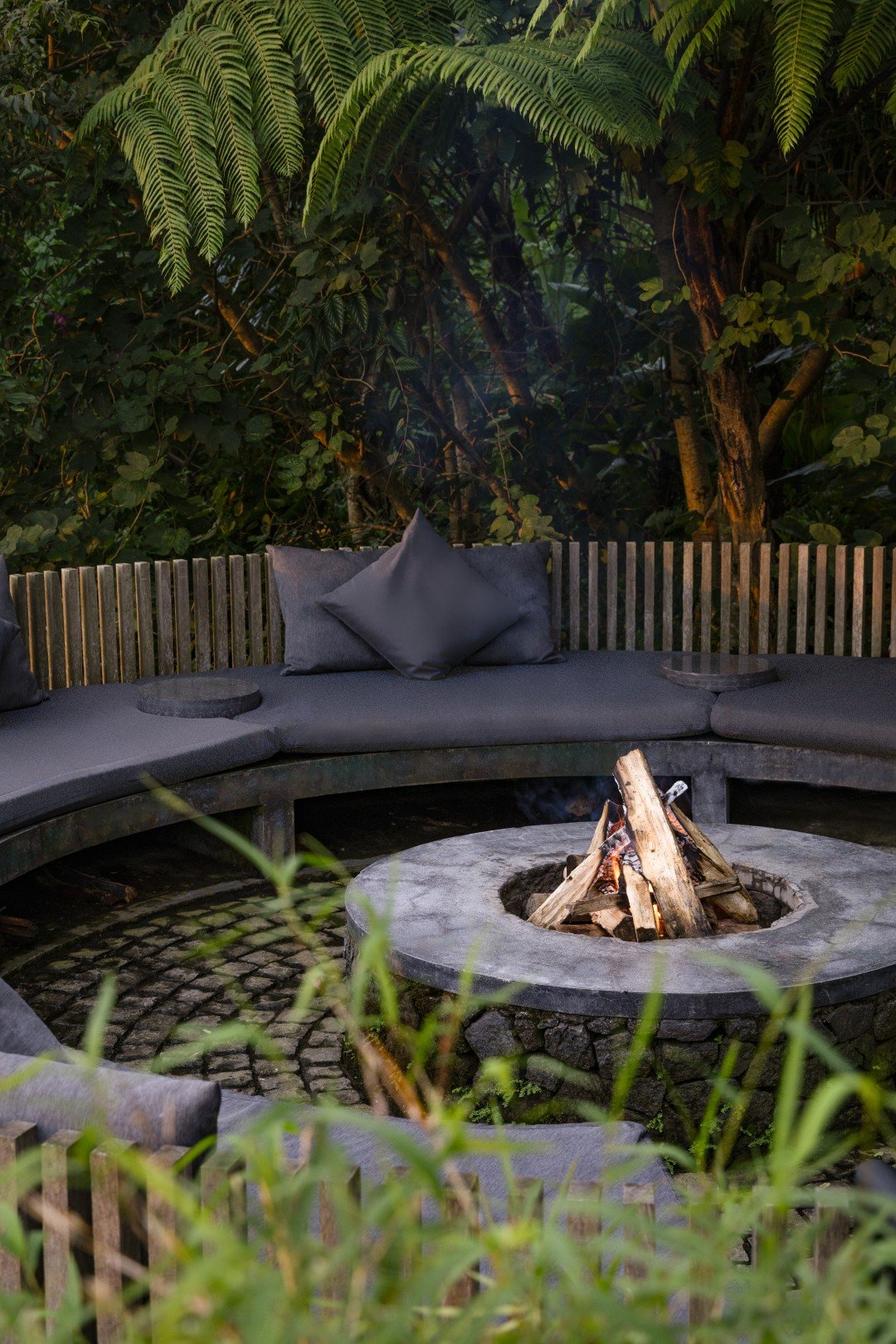 The fire pit at Munduk Cabins, ringed with cushioned seating under the tree ferns